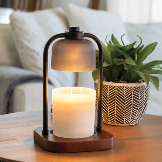 Decorative candle holder with a lit candle on a table next to a plant