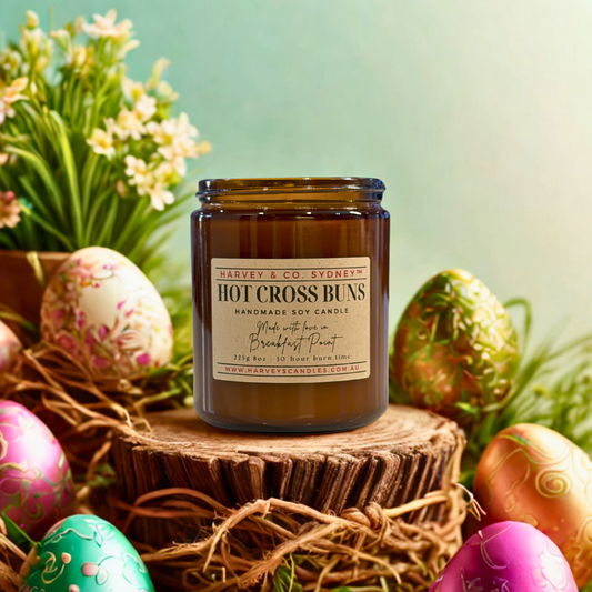 Harvey & Co. Sydney Hot Cross Buns candle with Easter eggs and flowers on a wooden stand.