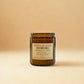 Soy jar candle in amber glass with spiced rum fragrance, shown in a close up with lid and label visible