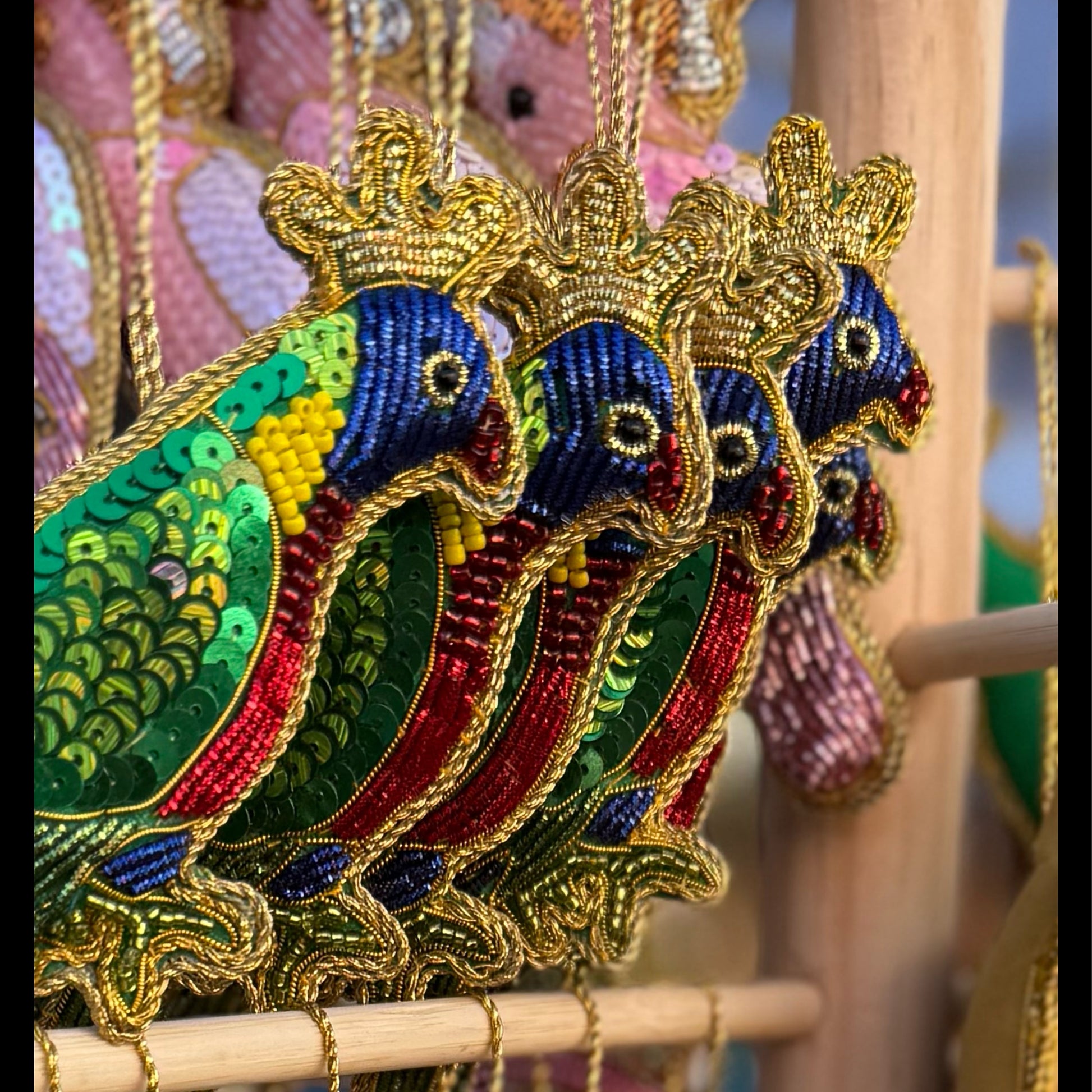 Colorful embroidered peacock designs on a wooden stand.