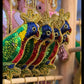 Colorful embroidered peacock designs on a wooden stand.